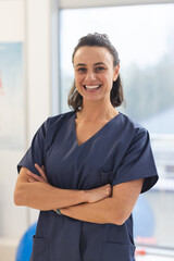 Portrait of happy female caucasian physiotherapist wearing scrubs at hospital