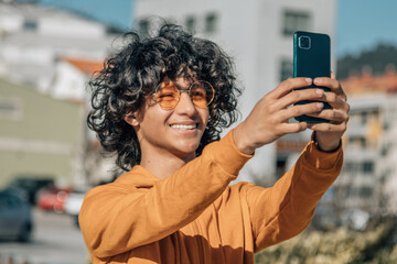 young man with phone taking a selfie or live video - Powered by Adobe