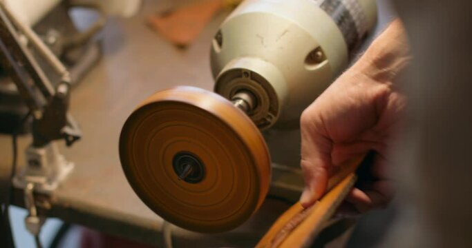 craftsman is working on leather polishing wheels at workshop Slow motion. Male hands of craftsman working with leather and grinding wheel. Working with genuine leather.