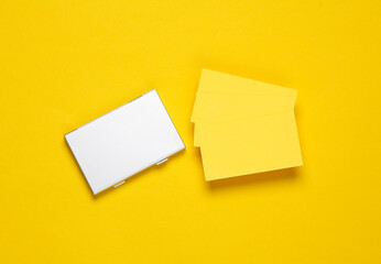 Metal box business card holder with business cards on a yellow background