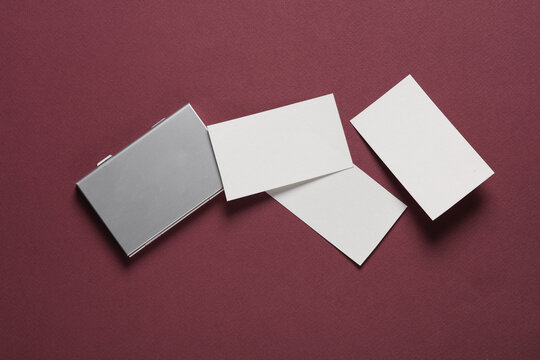 Metal box business card holder with business cards on burgundy background. Top view