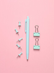 Fototapeta na wymiar Blue stationery accessories on pink background. Pen, paper clips, pins. Flat lay. Top view