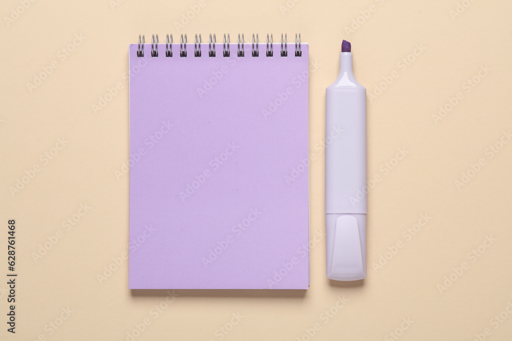 Poster notebook with a marker on a beige background. top view