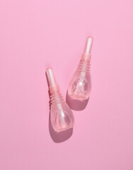 Two vaginal enemas on a pink background. Women's health