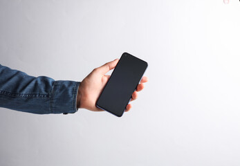 Hand in a denim shirt holding a smartphone on a gray background