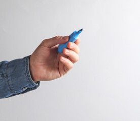 Man's hand in denim shirt holding blue marker on a gray background