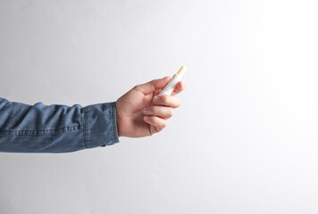 Man's hand in denim shirt holding lips balm on gray background.
