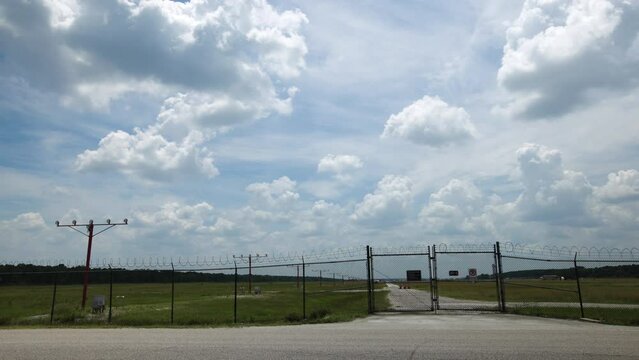 Airplane Crosses Fence To Land On Runway On Sunny Day