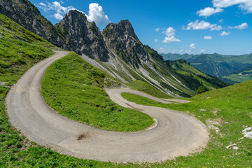 eine schmale Bergstrasse schlängelt sich den Berg hinunter in das Grosswalsertal, neben steinigen...