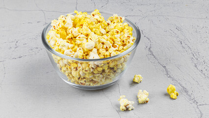 popcorn in a glass bowl on textured marble background with styling
