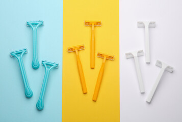 Set of plastic razors of different colors on three colored background