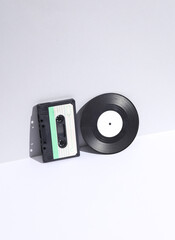 Retro 80s audio cassette and vinyl record on white background with shadow. Music lover. Creative layout, minimalism