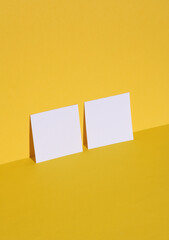 Square white memo papers on yellow background with shadow. Creative layout