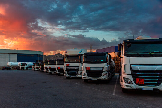 Several fuel tankers and other dangerous goods parked in a parking lot under a dramatic sky.