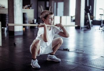 Children's fitness. A teenager trains with a body bar in a modern gym. Healthy lifestyle