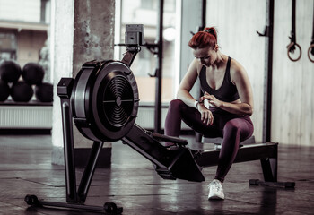 Fototapeta premium Athletic woman using smart watch in modern gym. Healthy lifestyle