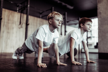Two teenagers do push-ups in the gym. Children's fitness. Healthy lifestyle