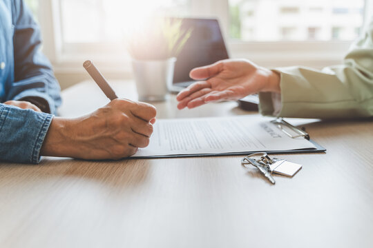 Real estate agent or realtor landlord advice buyer client to sign mortgage document. close-up focus on hand of tenant holding pen signing paperwork.