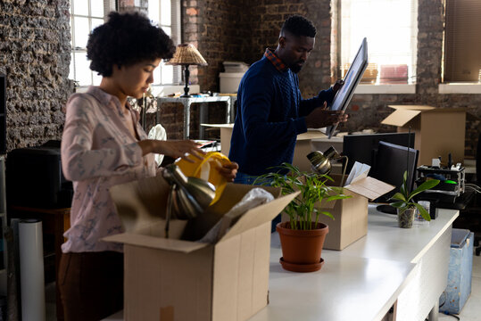Diverse male and female colleagues unpacking boxes, moving into office