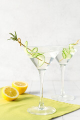 Glasses of tasty martini and lemon on white tile table