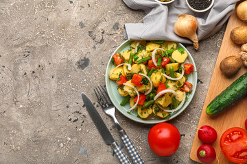Plate of tasty Potato Salad with vegetables and ingredients on grunge background