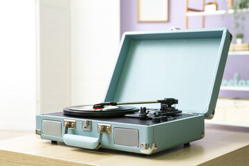 Record player with vinyl disk on table in room