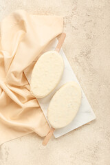 Board with tasty chocolate covered ice cream on light background