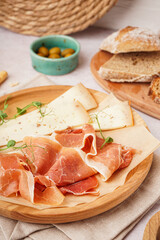 Plate with slices of tasty jamon and cheese on table, closeup