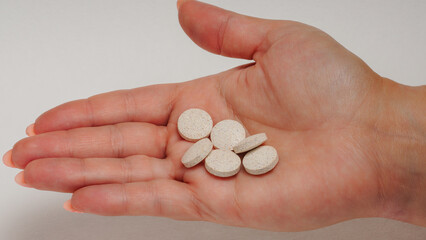 Different types of pills in a woman's hand