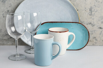 Set of different dishes on table near grey grunge wall
