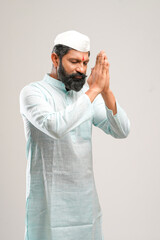 Indian man giving namaste or welcome gesture on white background.