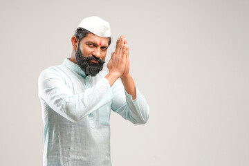 Indian man giving namaste or welcome gesture on white background.