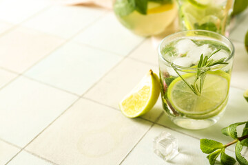 Glass of tasty mojito on light tile background