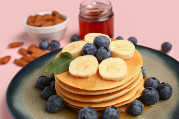 Plate with sweet pancakes, banana and blueberry on pink background, closeup