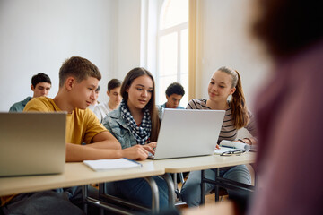 High school classmates using laptop during computer class in classroom.