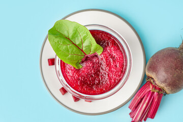 Plate with glass of healthy beet juice and spinach on blue background