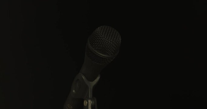 Microphone transitions from obscurity to illumination, then obscurity (fast)