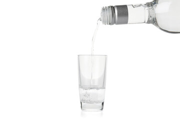 Pouring of vodka from bottle into glass on white background