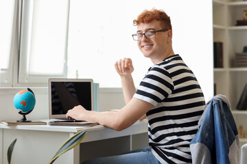 Fototapeta premium Young redhead man studying with laptop at home