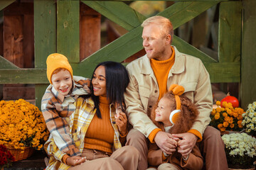 family traditions. multiethnic family i am in autumn in the park in a wooden gazebo next to pumpkins and flowers