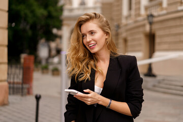 Attractive Vlond woman using mobyle phone , walking outdoor. Perfect blond hairs, casual outfit, sucsessful business woman.