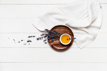 Fototapeta premium Plate with bowl of sweet lavender honey and flowers on white wooden background