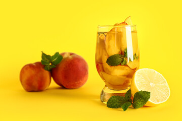 Fototapeta premium Glass of fresh peach lemonade with mint on yellow background