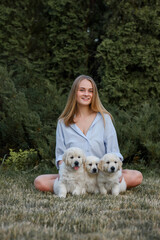 beautiful girl with dogs golden retriever puppies on a walk in summer