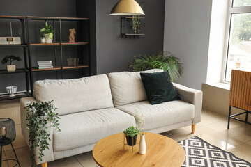 Interior of modern living room with comfortable grey sofa and wooden coffee table