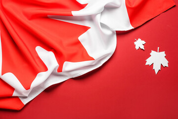 Flag of Canada and paper maple leaves on red background