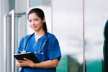 Asian nurse or doctor with stethoscope and clipboard in hospital.