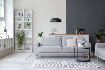 Interior of light living room with comfortable grey sofa and coffee table