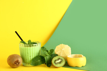 Glass of fresh kiwi smoothie with mint and lemon on colorful background