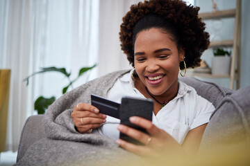 Happy black woman, phone and credit card for ecommerce, payment or fintech banking on sofa at home....